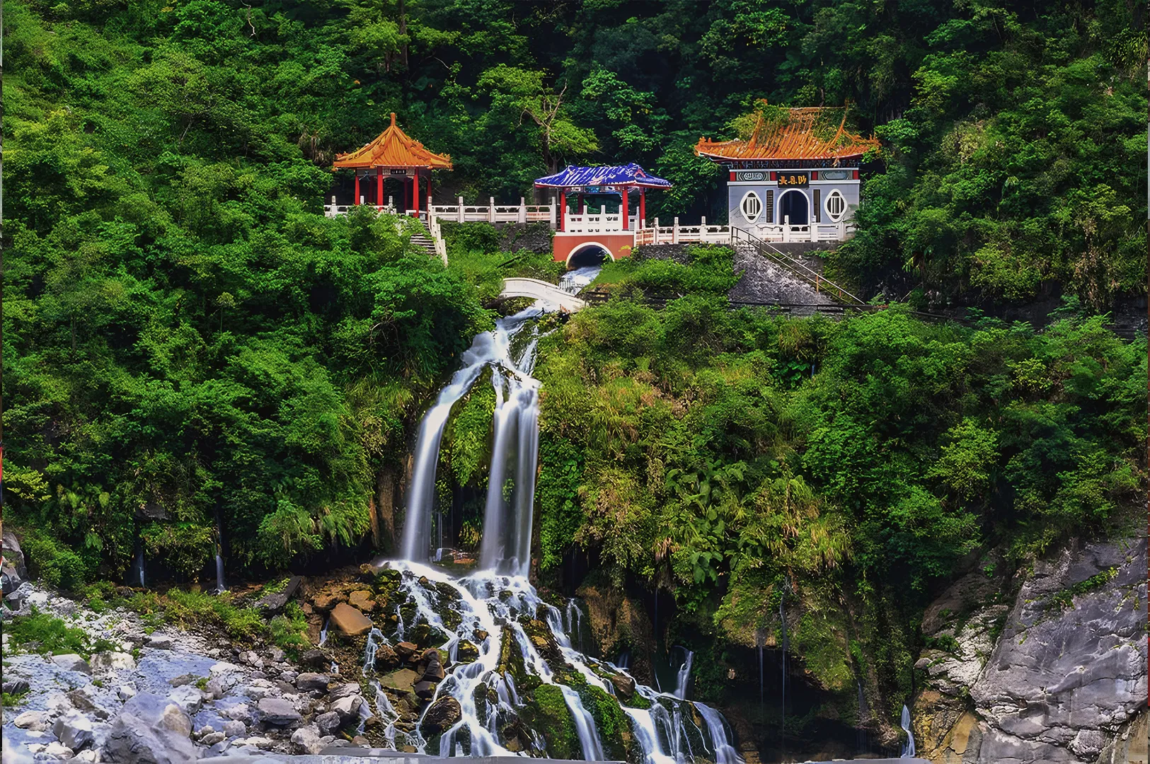 Traditional Chinese shrine and pagodas nestled in a lush green mountain forest above Changchun Shrine waterfall in Taroko Gorge.