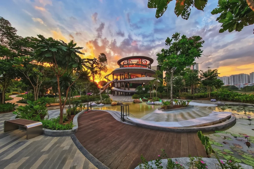Sunset view of Bishan‑Ang Mo Kio Park in Singapore featuring modern spiral pavilion, landscaped pond, and lush greenery — scenic urban park design.
