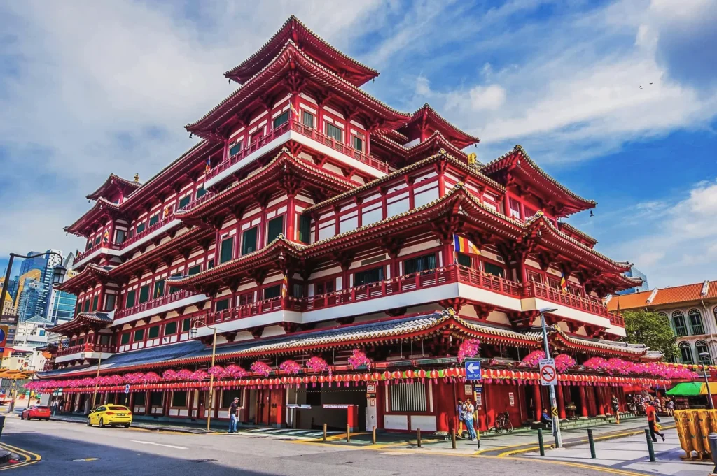 Majestic Buddha Tooth Relic Temple in Chinatown, Singapore, showcasing traditional red and white pagoda architecture with golden roof details and festive lantern decorations.