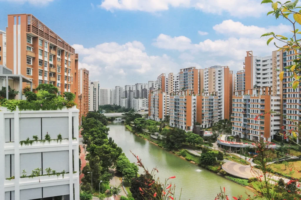 Aerial view of Singapore’s residential district with high‑rise apartments along a landscaped canal — modern eco‑friendly urban living surrounded by greenery.