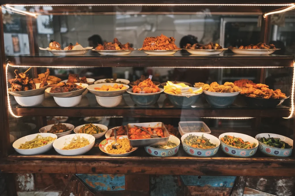 Traditional Indonesian dishes and side dishes displayed inside a wooden glass food cabinet at a local warung in Bali