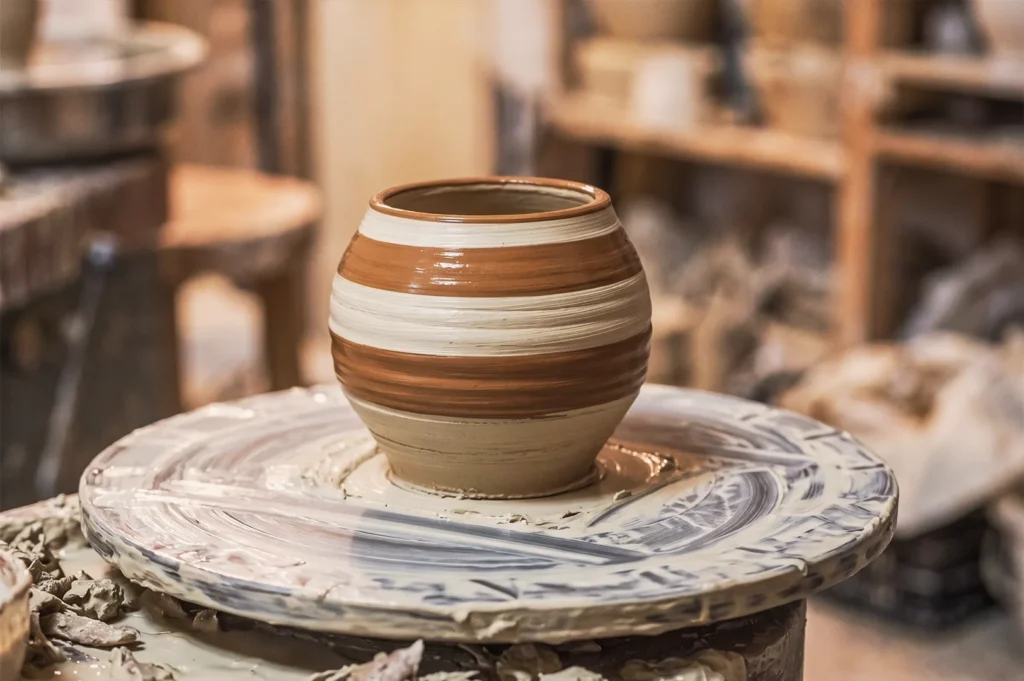 Brown and beige striped clay pot on pottery wheel at Taoz Ceramics Studio — showcasing traditional ceramic craftsmanship and wheel‑throwing technique.