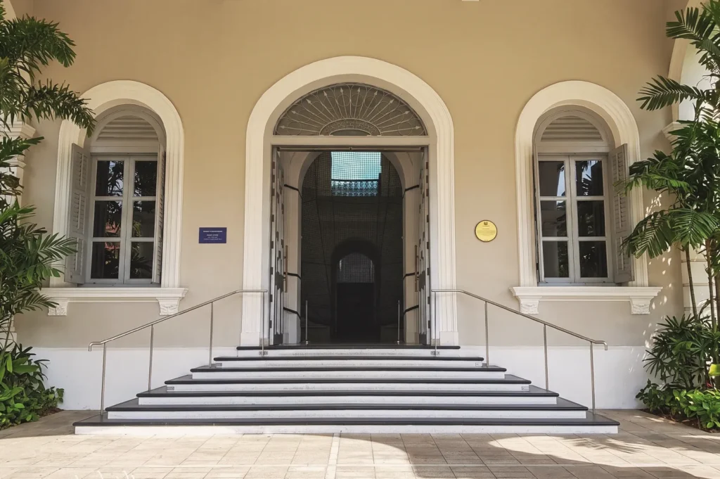 Colonial‑style doorway with arched windows, fanlight design, and surrounding tropical greenery, showcasing heritage architecture.